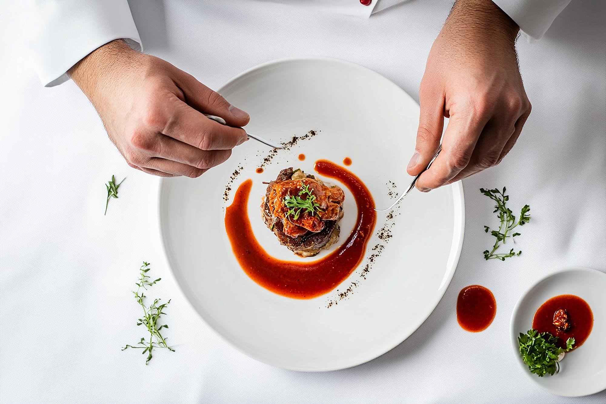 Chef arranging plated gourmet dish on table
